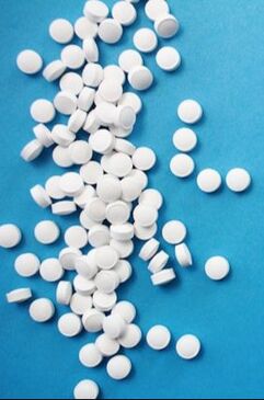 Photo shows round white pills on a blue background.